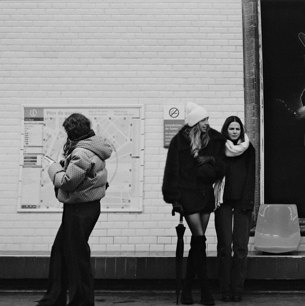 Young Chilean woman waiting at a metro station platform looking at her phone