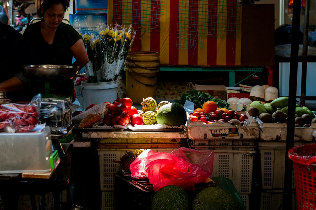 Chilean market vendor standing behind a stall of fresh fruit and vegetables